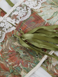 Decorative box with floral pattern and green ribbons on a white background